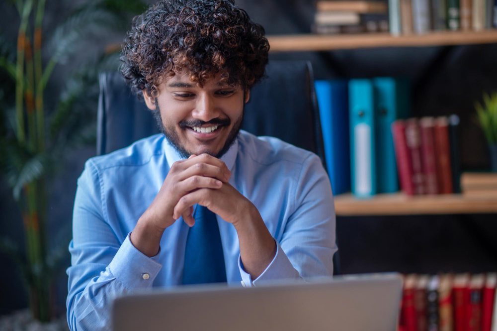 Man smiling while working on a laptop