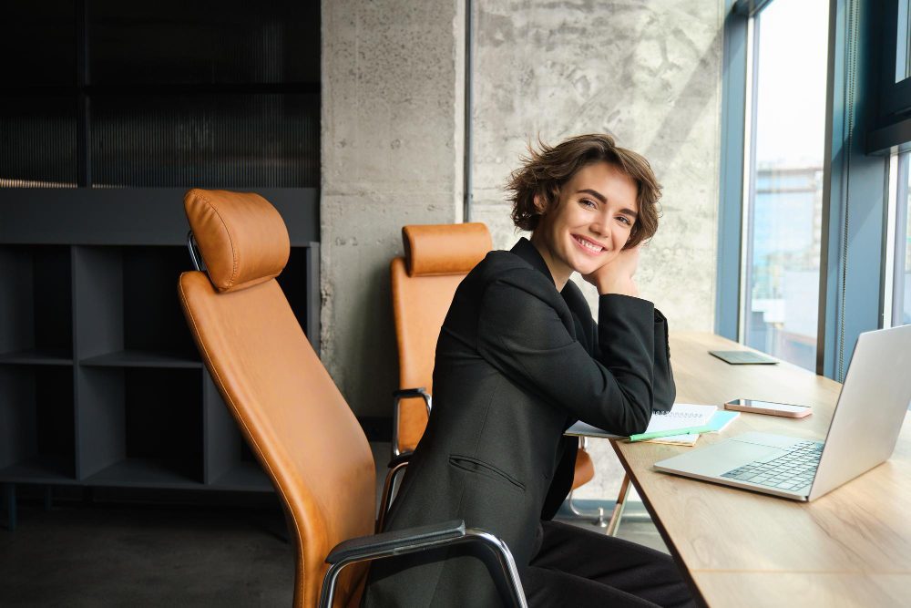 Woman smiling confidently at her desk in a modern office