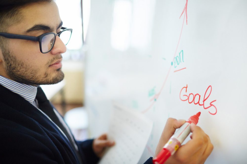 Hand writing financial goals on a whiteboard